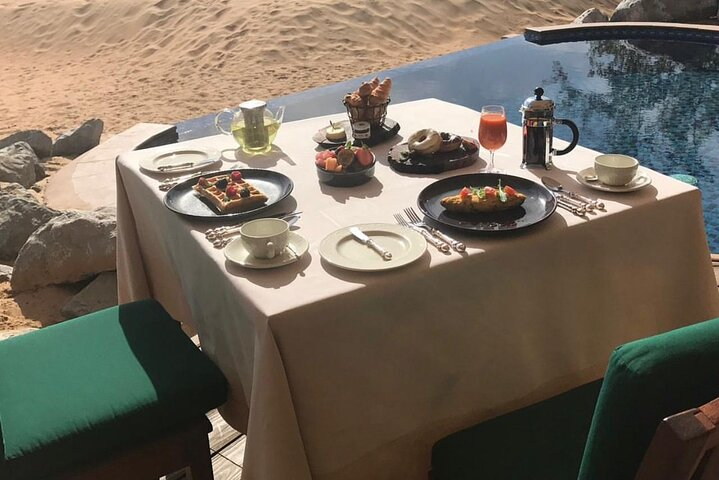 Savor a delicious breakfast overlooking the serene sands of the Dubai desert where stunning sunrises create a perfect backdrop for unforgettable memories and culinary delights.